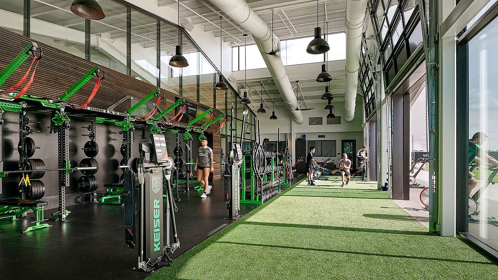 A room with a few people and a large display of computer equipment.